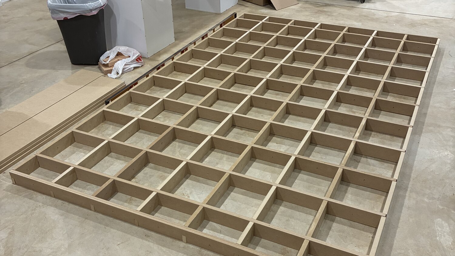 The assembled egg crate core lying on the shop floor, dozens of interlocking MDF ribs forming a grid roughly five feet by nine feet